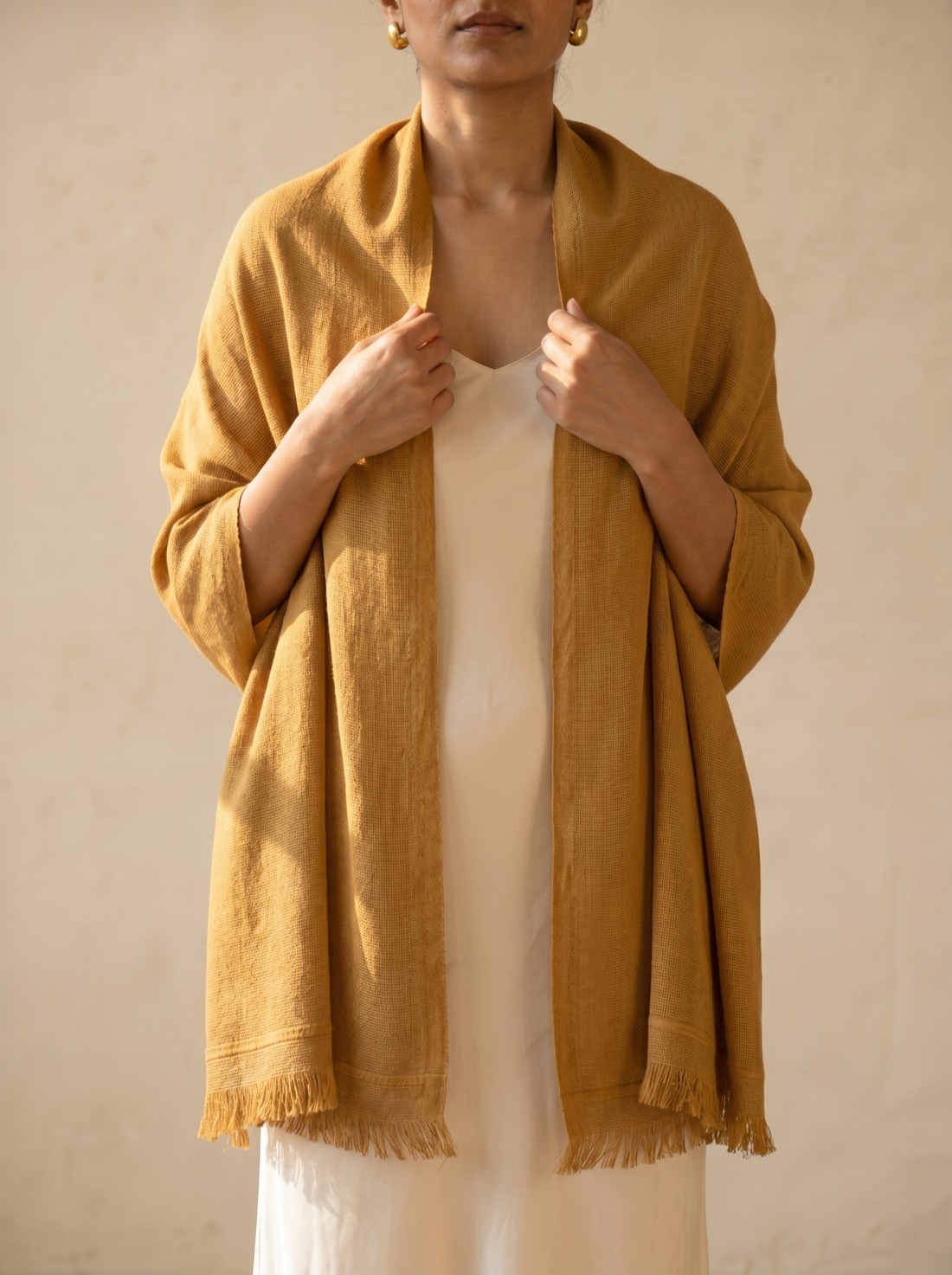 The Noorbaft shawl in Zaffran saffron gold, draped over a model's shoulders